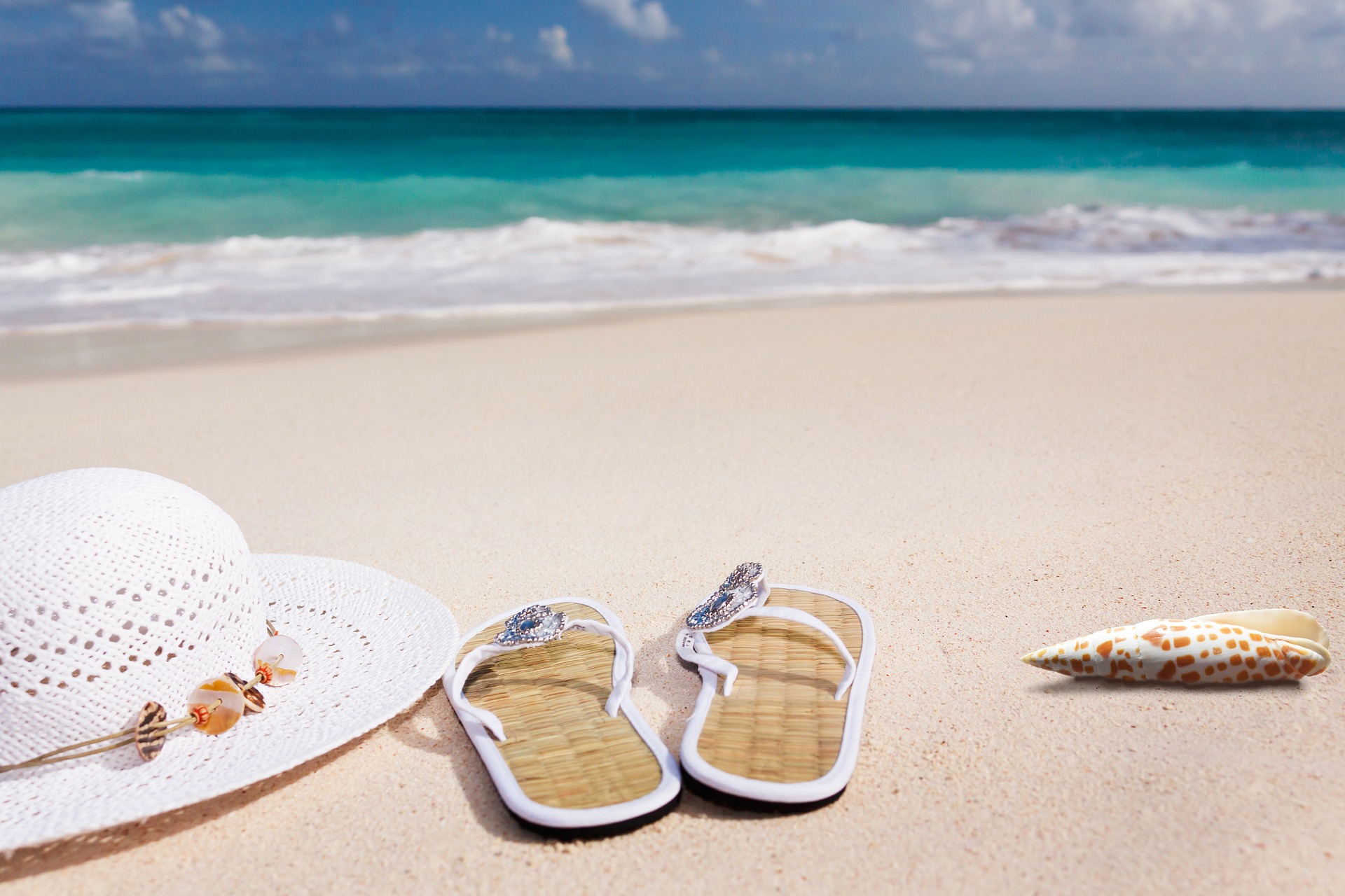 A sunhat, flipflops and shell on a beautiful beach